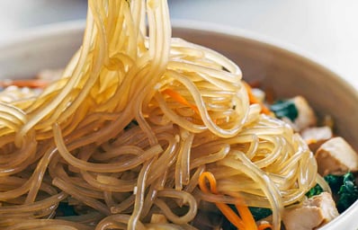 japchae korean glass noodles in sauce with chopsticks