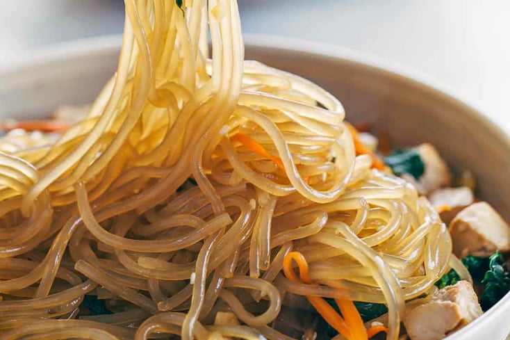 japchae korean glass noodles in sauce with chopsticks