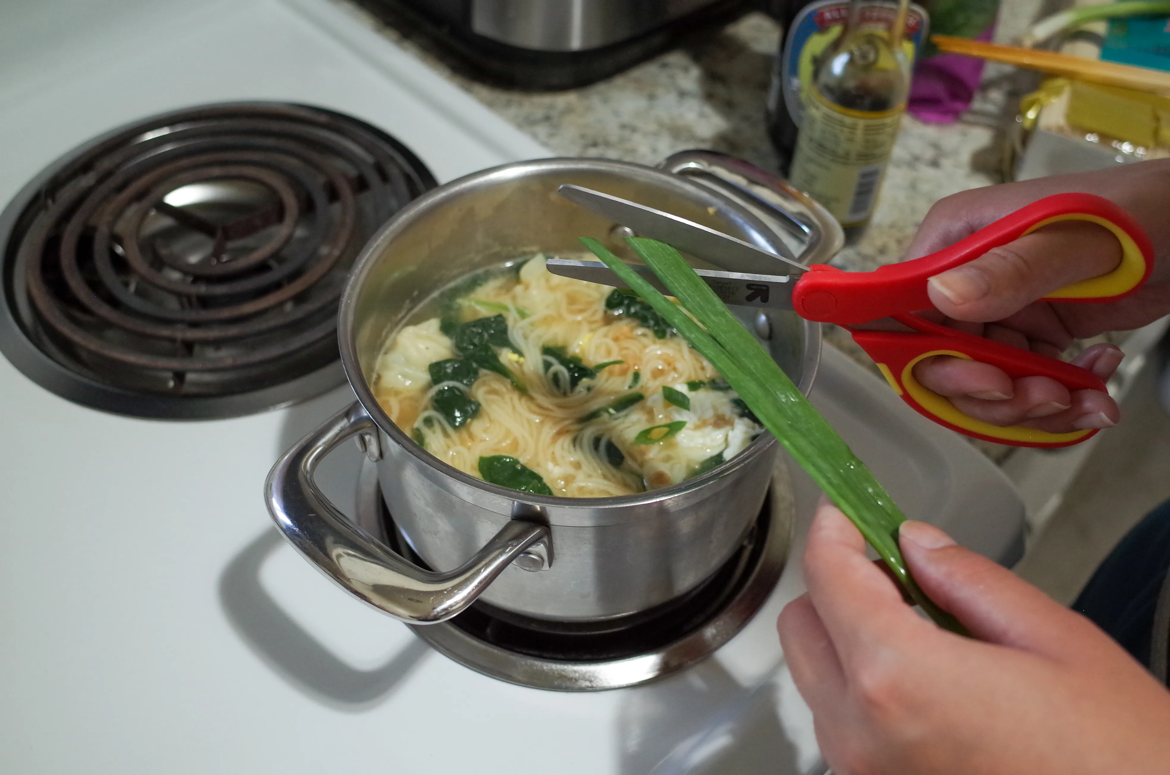 Cutting green onions over pot